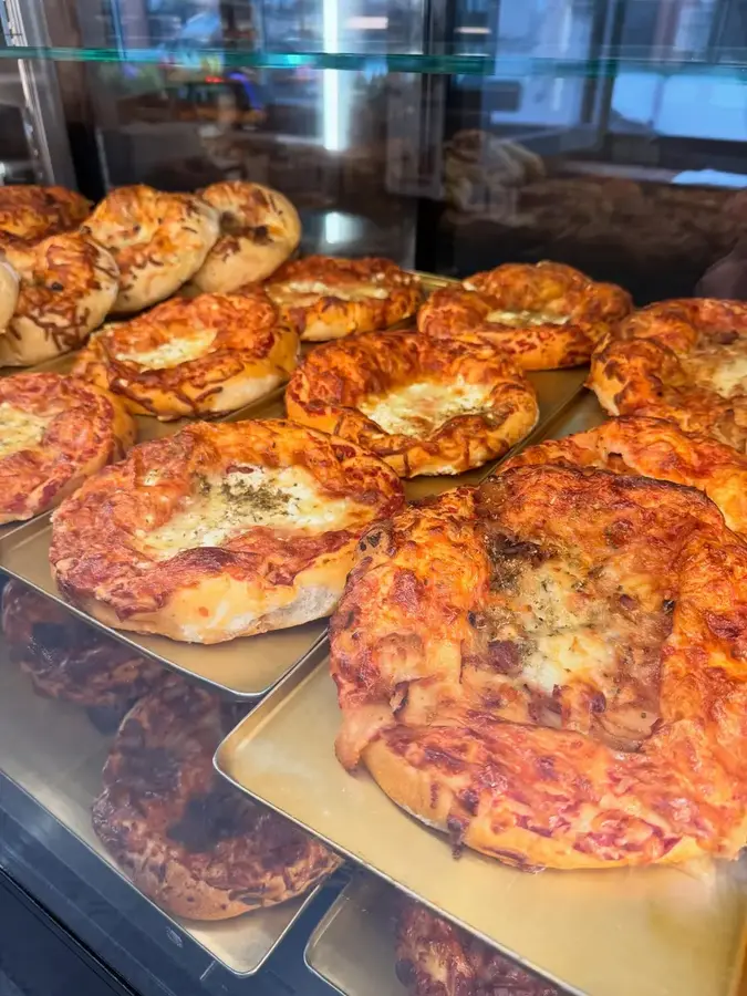 Nybakte pizzaer og varm bakst i disken hos Mediterranean Bakeri
